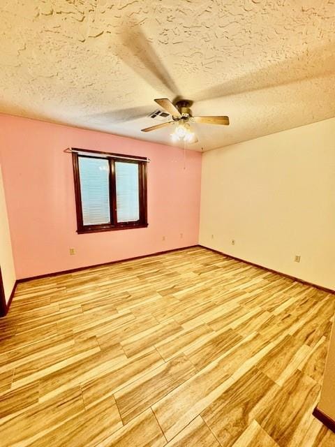 spare room featuring a textured ceiling, light wood-type flooring, and ceiling fan