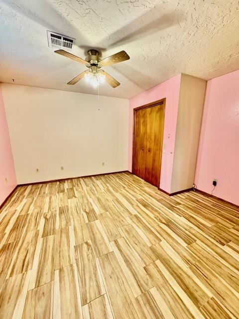 unfurnished bedroom featuring ceiling fan, a textured ceiling, and light wood-type flooring