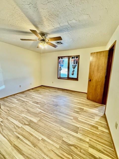 spare room with a textured ceiling, light hardwood / wood-style flooring, and ceiling fan