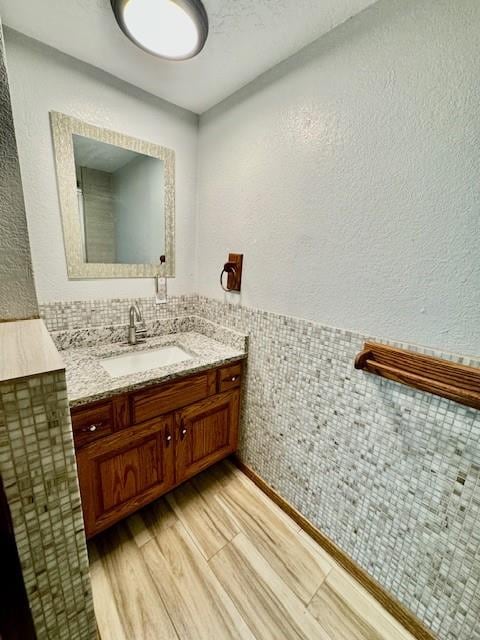 bathroom with hardwood / wood-style floors, vanity, and tile walls