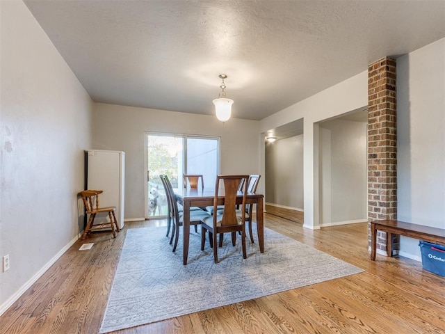 dining area with a textured ceiling and light hardwood / wood-style flooring