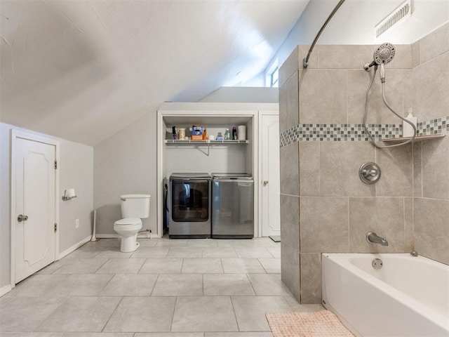 bathroom featuring toilet, vaulted ceiling, tiled shower / bath combo, washer and clothes dryer, and tile patterned flooring