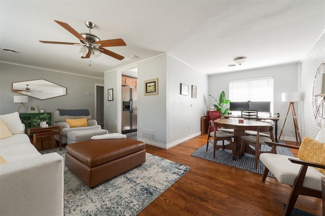 living room with dark wood-type flooring, ceiling fan, and crown molding