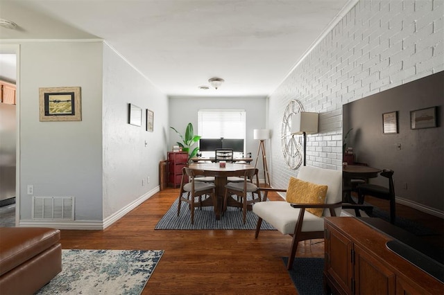 dining room featuring brick wall and wood-type flooring