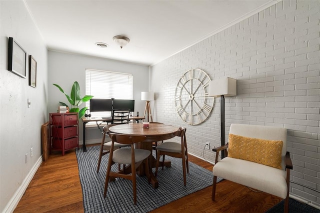 dining space featuring brick wall, wood-type flooring, and crown molding