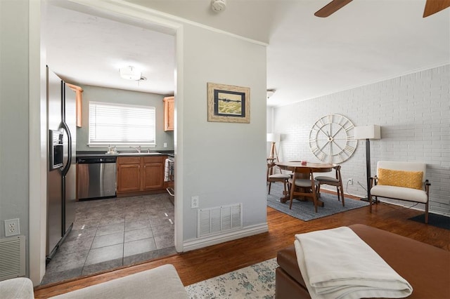 interior space with brick wall, ceiling fan, and dark wood-type flooring