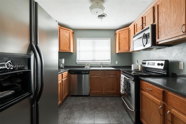 kitchen featuring stainless steel appliances, dark tile patterned flooring, and sink