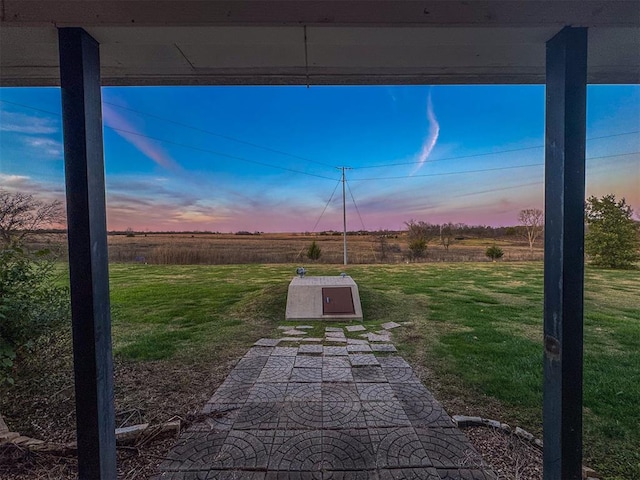 yard at dusk featuring a rural view