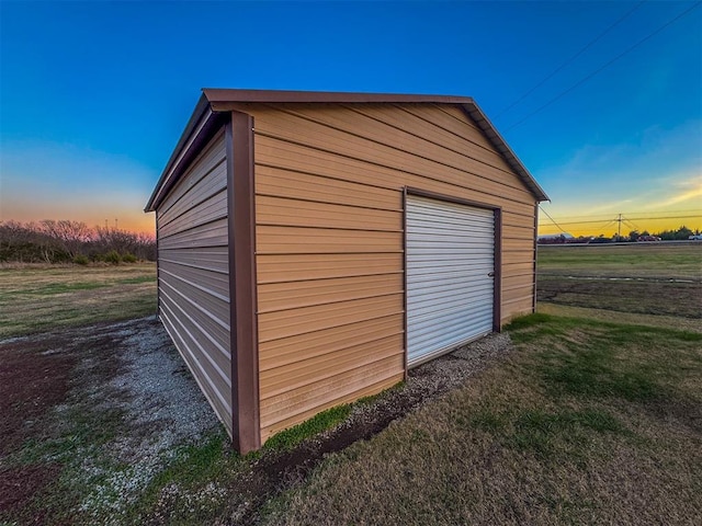 outdoor structure at dusk featuring a lawn and a garage