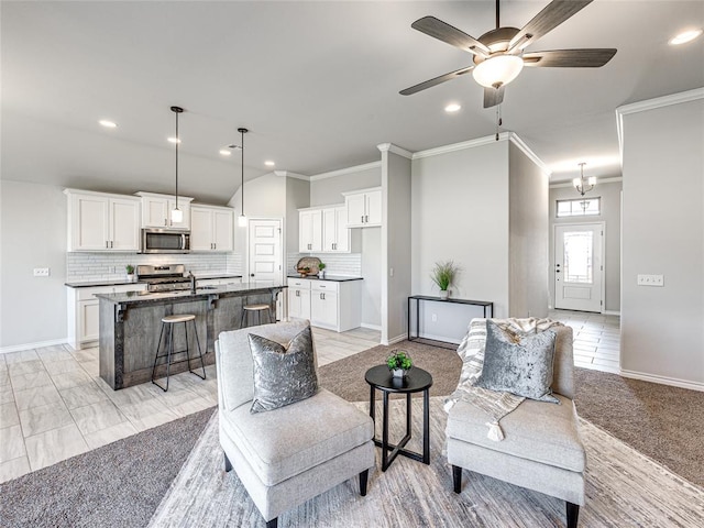 living room featuring ceiling fan with notable chandelier, ornamental molding, sink, and light tile patterned floors