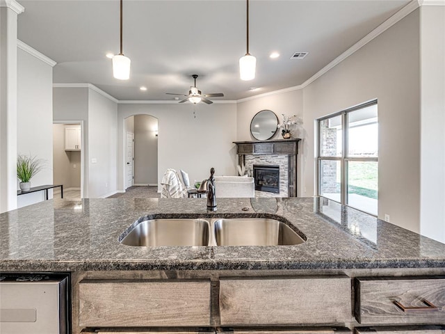 kitchen featuring dark stone countertops, crown molding, ceiling fan, and decorative light fixtures