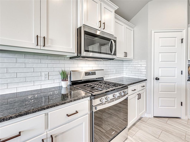 kitchen with decorative backsplash, appliances with stainless steel finishes, white cabinetry, and dark stone countertops