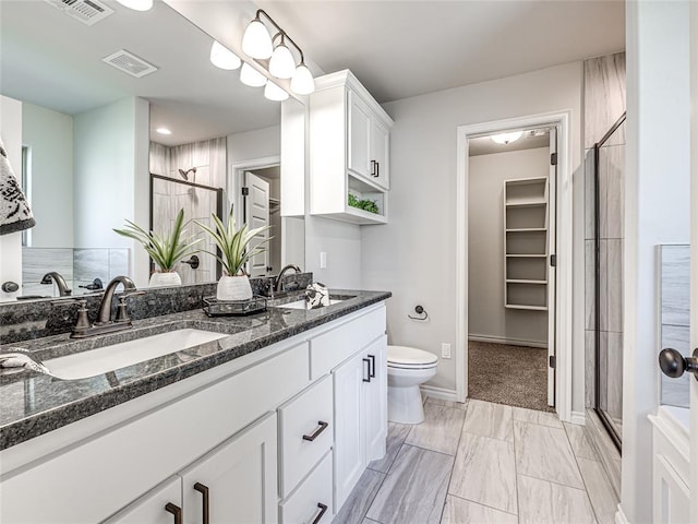 bathroom featuring a shower with door, vanity, and toilet