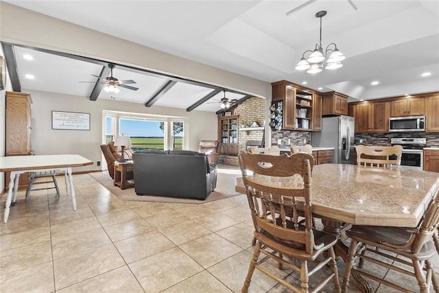 dining room featuring vaulted ceiling with beams, light tile patterned floors, a fireplace, and ceiling fan with notable chandelier