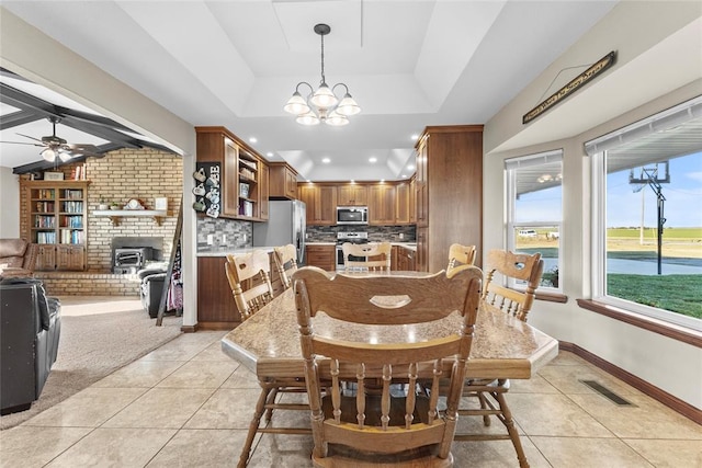 dining room featuring light tile patterned floors, ceiling fan with notable chandelier, and a raised ceiling