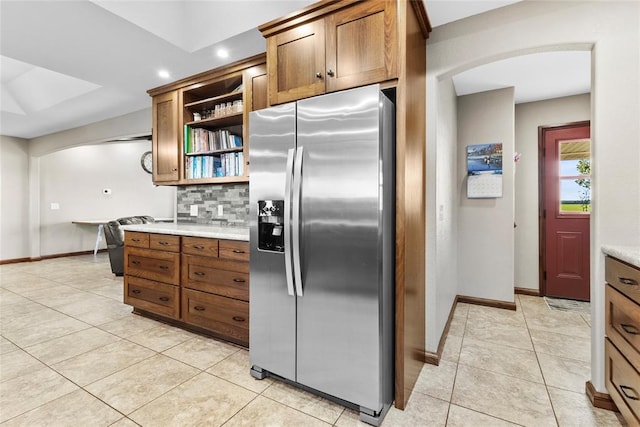 kitchen featuring stainless steel fridge, backsplash, and light tile patterned floors