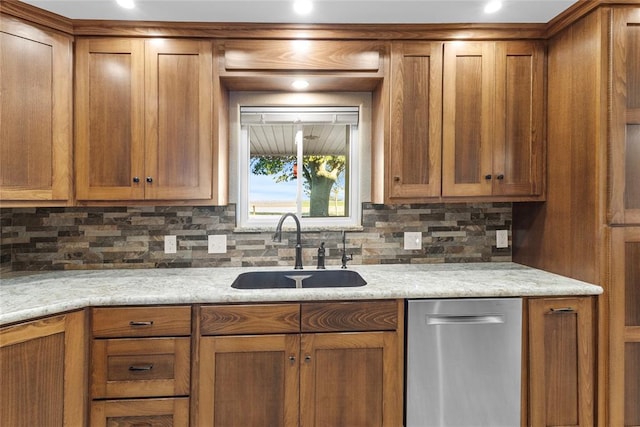 kitchen featuring tasteful backsplash, light stone counters, sink, and stainless steel dishwasher