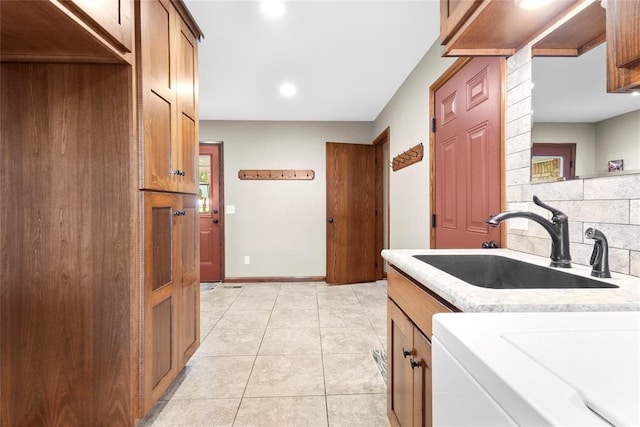 laundry area featuring cabinets, light tile patterned floors, and sink