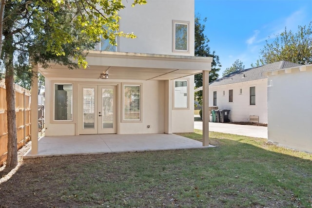 rear view of house with french doors, a patio, and a lawn