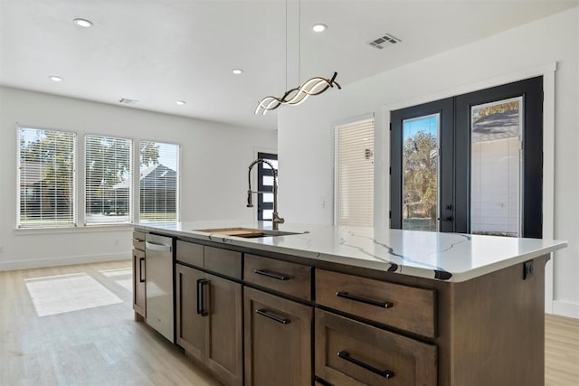 kitchen with decorative light fixtures, a healthy amount of sunlight, sink, and a kitchen island with sink