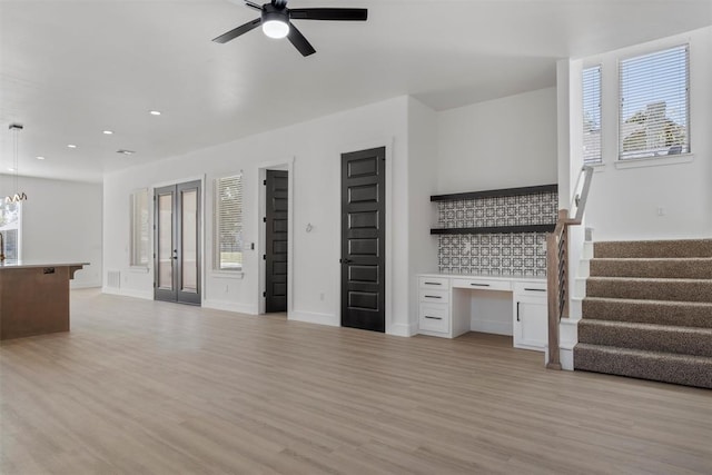 unfurnished living room featuring plenty of natural light, light hardwood / wood-style floors, and ceiling fan with notable chandelier