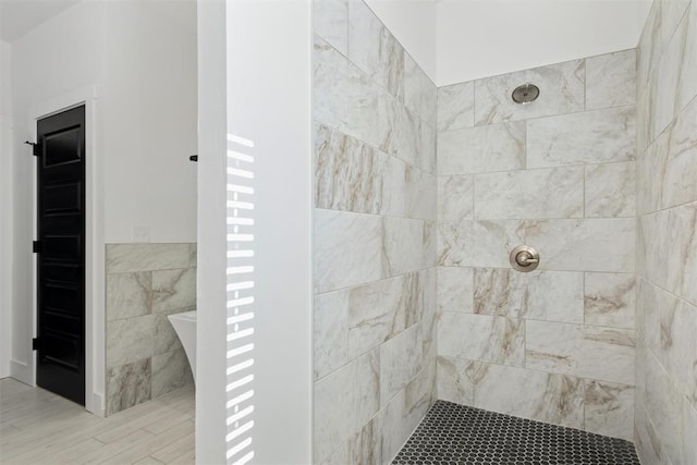 bathroom with a tile shower and hardwood / wood-style floors