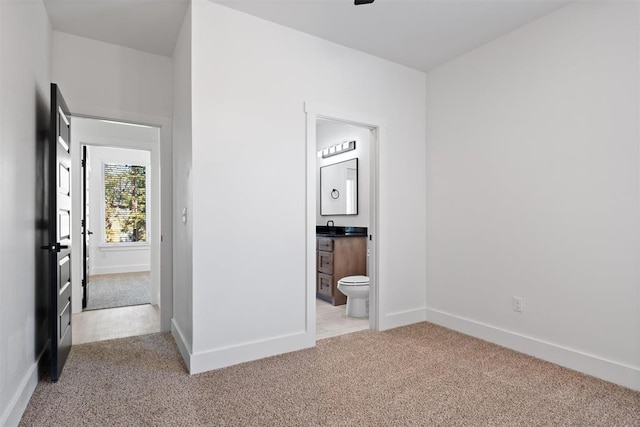 interior space with connected bathroom and light colored carpet