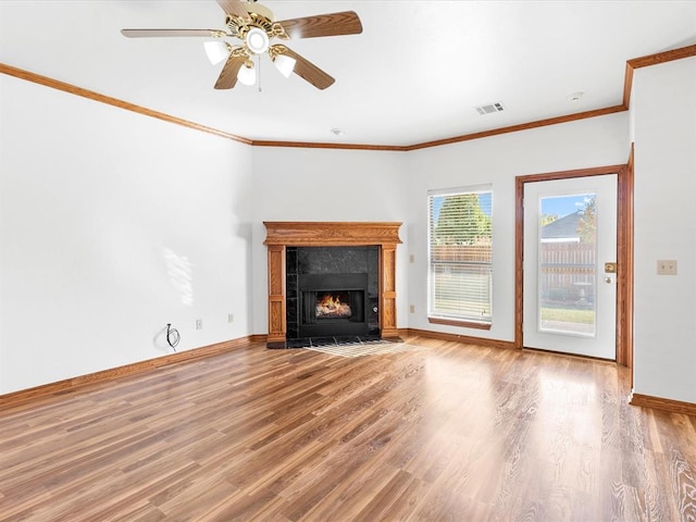 unfurnished living room with hardwood / wood-style flooring, ceiling fan, ornamental molding, and a fireplace