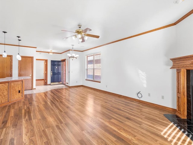 unfurnished living room featuring hardwood / wood-style floors, ceiling fan with notable chandelier, ornamental molding, and a tile fireplace