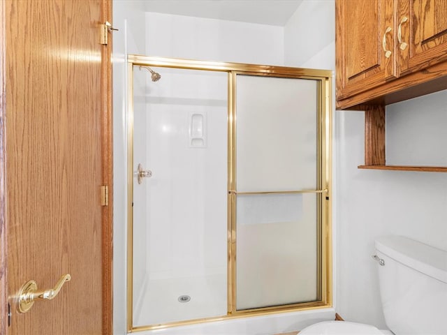 bathroom featuring toilet and a shower with shower door