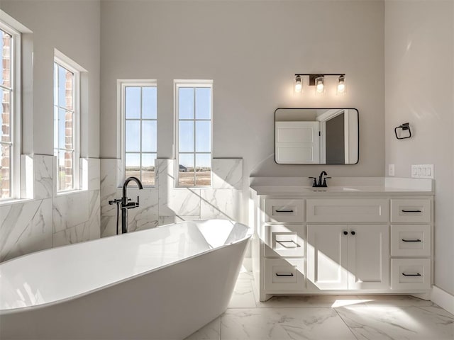 bathroom featuring vanity, a tub to relax in, and tile walls