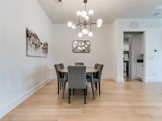 dining area with light wood-type flooring and a notable chandelier