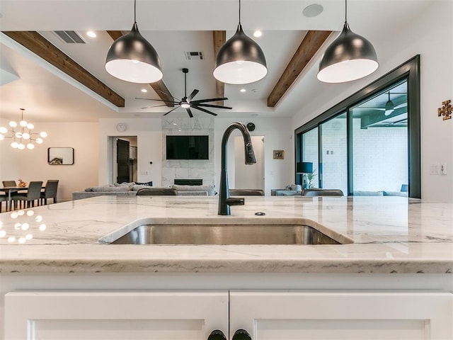 kitchen with decorative light fixtures, light stone counters, and sink