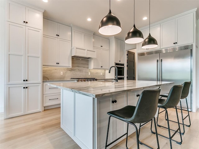 kitchen with white cabinets, sink, and a large island with sink