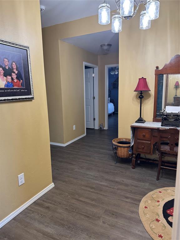 hallway featuring dark hardwood / wood-style floors and an inviting chandelier