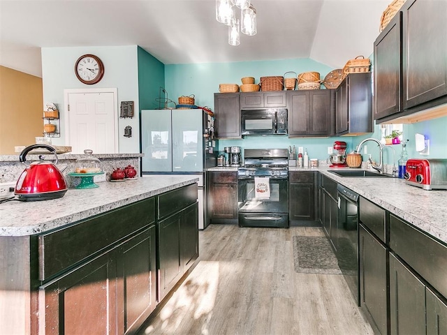 kitchen featuring black appliances, sink, vaulted ceiling, light hardwood / wood-style flooring, and dark brown cabinets