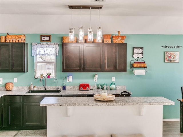 kitchen with a breakfast bar, dark brown cabinets, decorative light fixtures, and sink