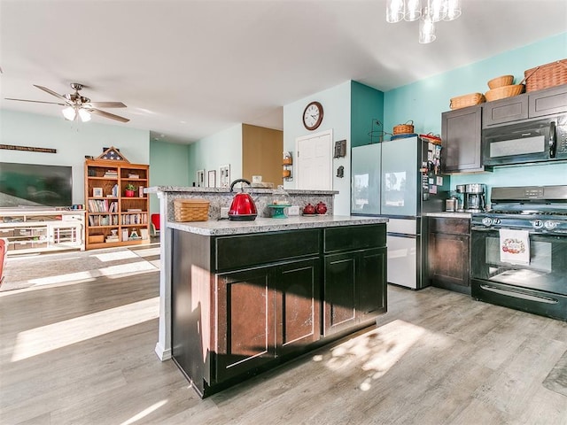 kitchen featuring ceiling fan, light hardwood / wood-style flooring, a kitchen island, and black appliances