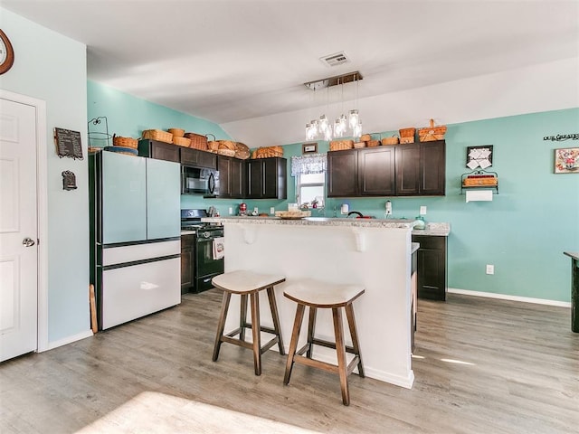 kitchen featuring a center island, a kitchen breakfast bar, decorative light fixtures, dark brown cabinets, and black appliances