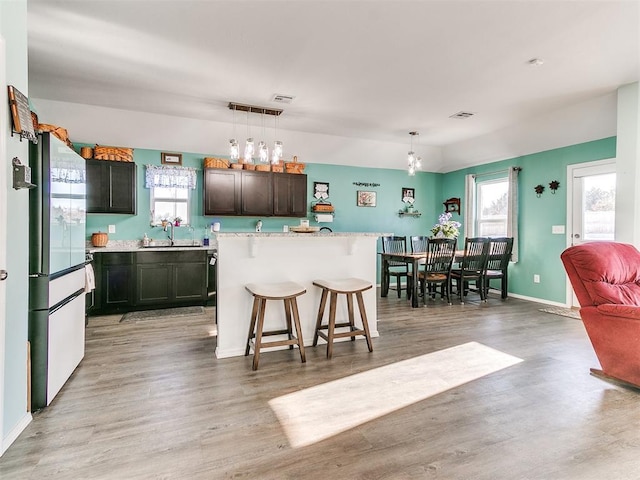 kitchen featuring pendant lighting, a center island, white refrigerator, and a breakfast bar area