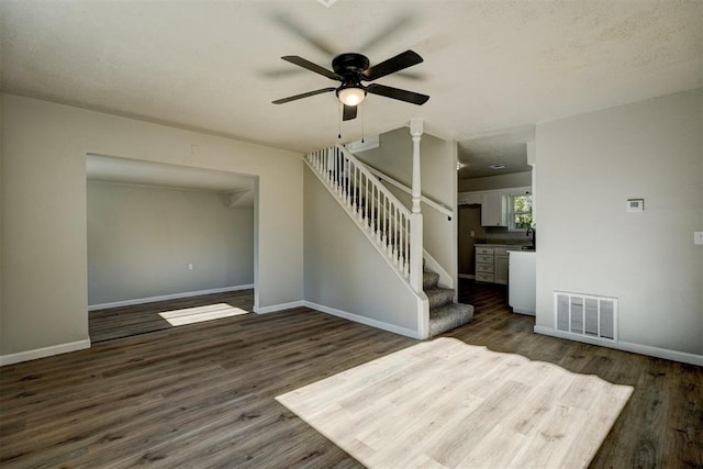 interior space featuring a textured ceiling, ceiling fan, and dark wood-type flooring