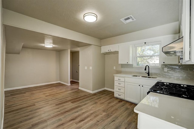 kitchen featuring backsplash, ventilation hood, sink, light hardwood / wood-style flooring, and white cabinetry