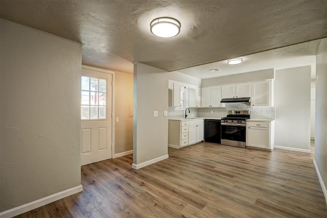 kitchen featuring black dishwasher, stainless steel gas range oven, backsplash, light hardwood / wood-style floors, and white cabinets