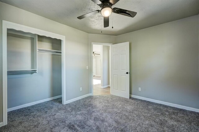 unfurnished bedroom with ceiling fan, carpet floors, a textured ceiling, and a closet