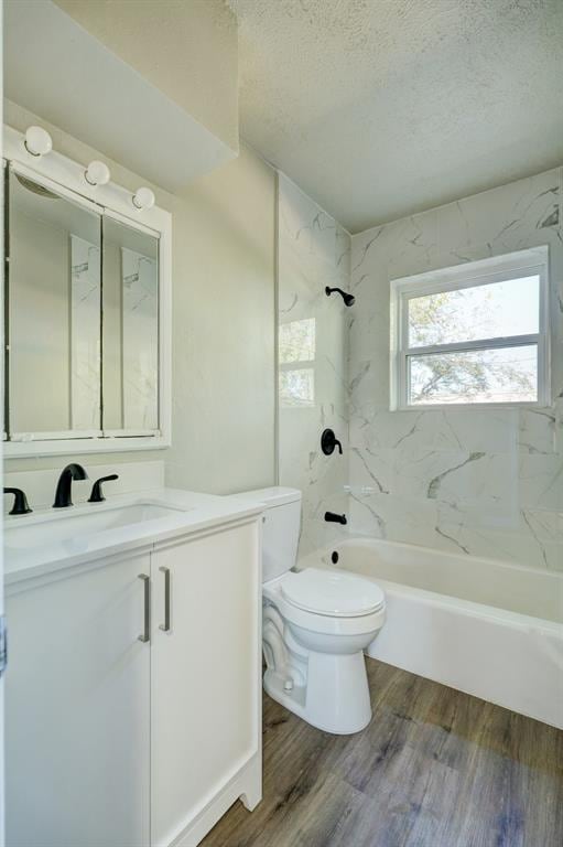 full bathroom with tiled shower / bath combo, a textured ceiling, toilet, vanity, and hardwood / wood-style flooring