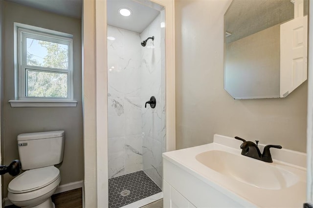 bathroom with tiled shower, vanity, and toilet