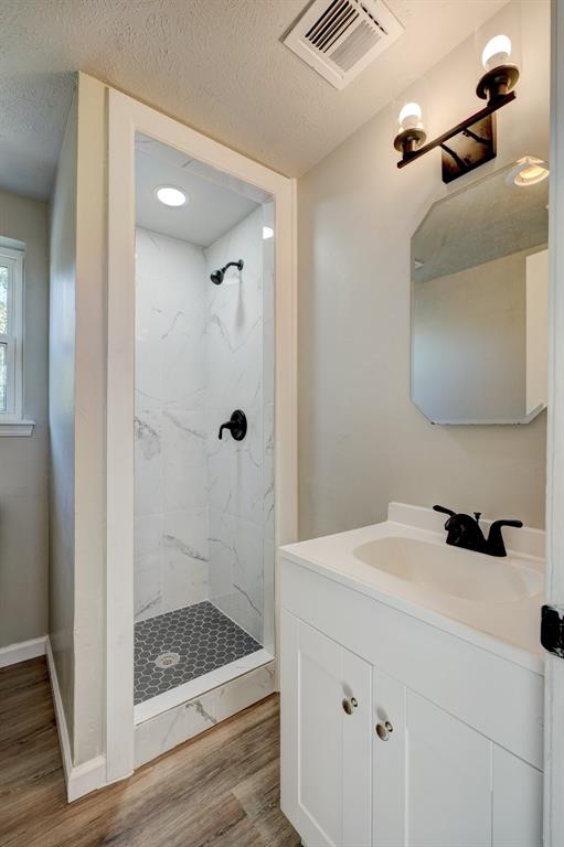 bathroom featuring hardwood / wood-style flooring, a tile shower, and a textured ceiling