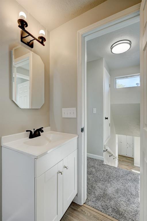 bathroom with hardwood / wood-style floors, vanity, and a textured ceiling