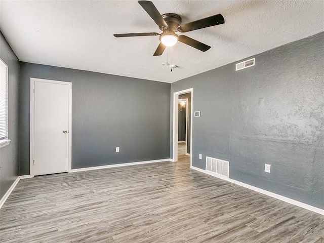 unfurnished room featuring hardwood / wood-style flooring, ceiling fan, and a textured ceiling