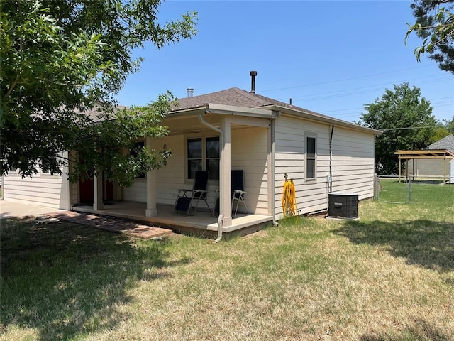 back of house featuring central AC unit and a lawn